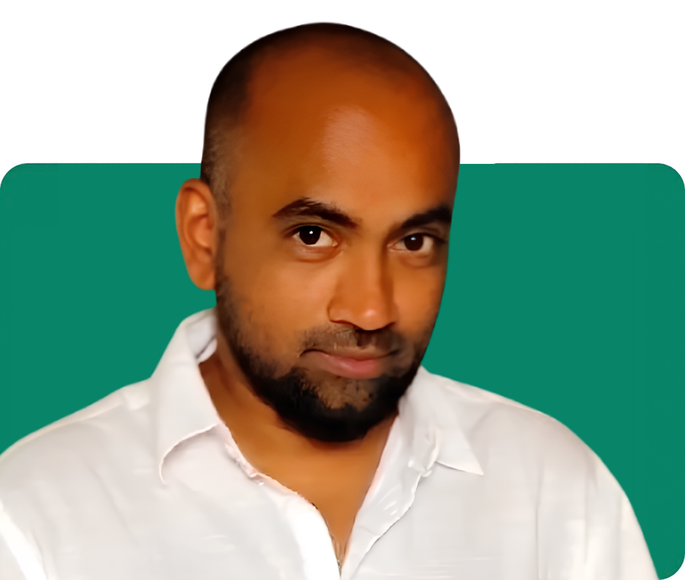 A confident individual with a shaved head and beard, wearing a white shirt, against a green background.